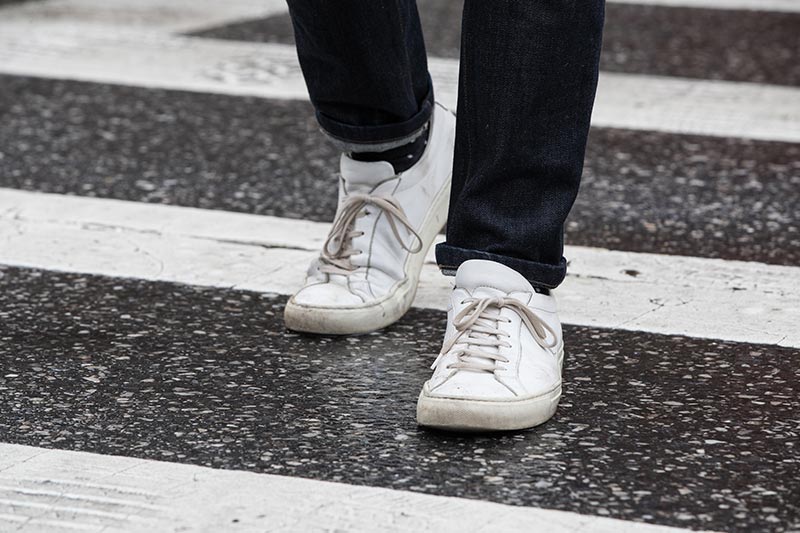 white-leather-sneakers-with-rolled-jeans-crossing-crosswalk