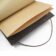 Brown leather notebook with kraft paper pages, staple binding and elastic closure, a close-up detail