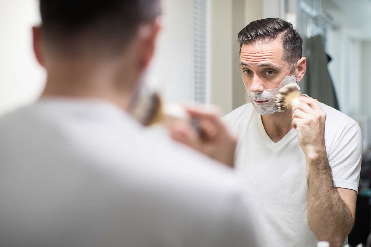 A man uses a shaving brush as part of skincare routine
