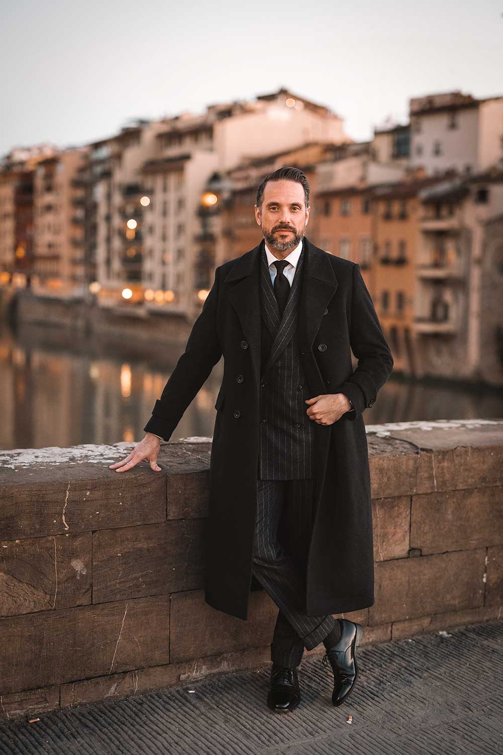 brian sacawa at pitti uomo 103 wearing a charcoal greatcoat near the ponte vecchio