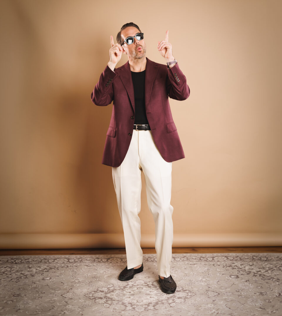 Burgundy wool sport coat with black tee, cream trousers and brown tassel loafers, worn by a model
