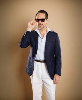 Navy hopsack sport coat with blue striped shirt and white linen trousers, worn by a model