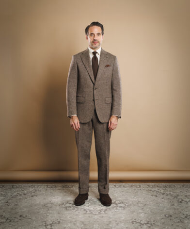 Brown Donegal tweed suit with white shirt, brown knit tie and suede loafers, worn by a model