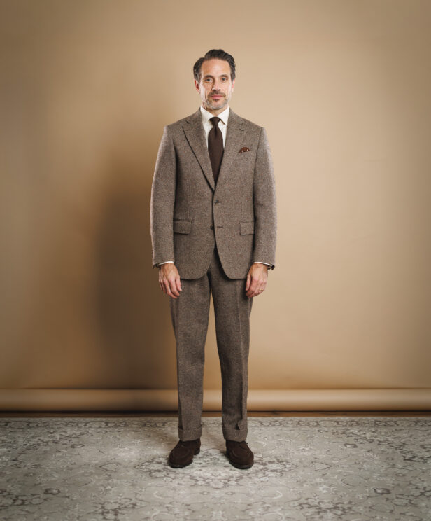 Brown Donegal tweed suit with white shirt, brown knit tie and suede loafers, worn by a model