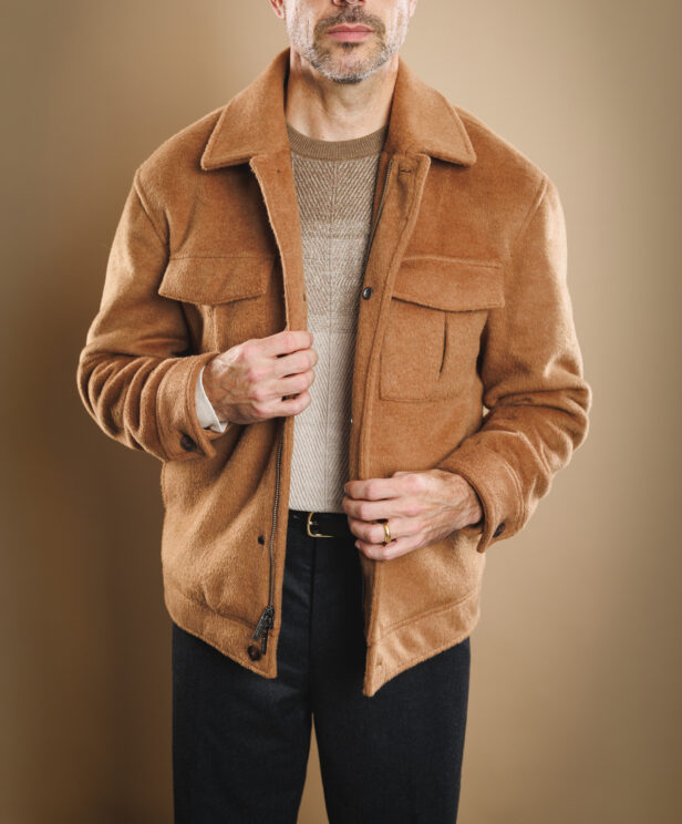 Camel brushed wool zip blouson with chest pockets over a beige knit sweater and charcoal flannel trousers, worn by a model