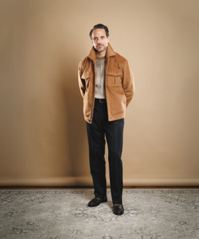 Camel wool zip jacket with patch pockets, worn with a tan sweater and navy flannel trousers by a model