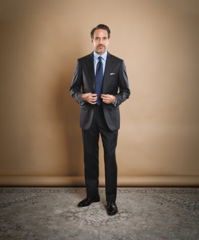 Charcoal striped two-button suit with light blue shirt, navy dotted tie and white pocket square, worn by a model