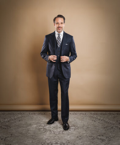 Navy three-piece suit with white shirt, striped tie and pocket square, worn by a model