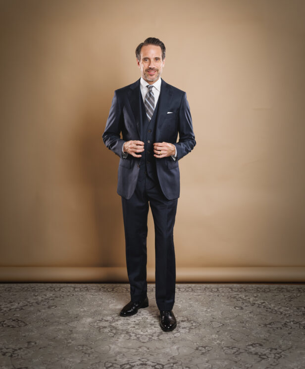 Navy three-piece suit with white shirt, striped tie and pocket square, worn by a model