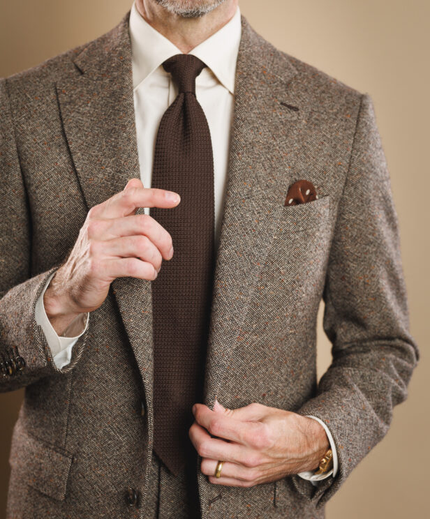 Brown donegal tweed sport coat with cream shirt, brown knit tie and patterned pocket square, worn by a model